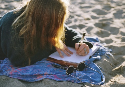 Girl journaling on sand