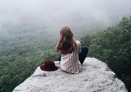 girl sitting on a rock looking at trees